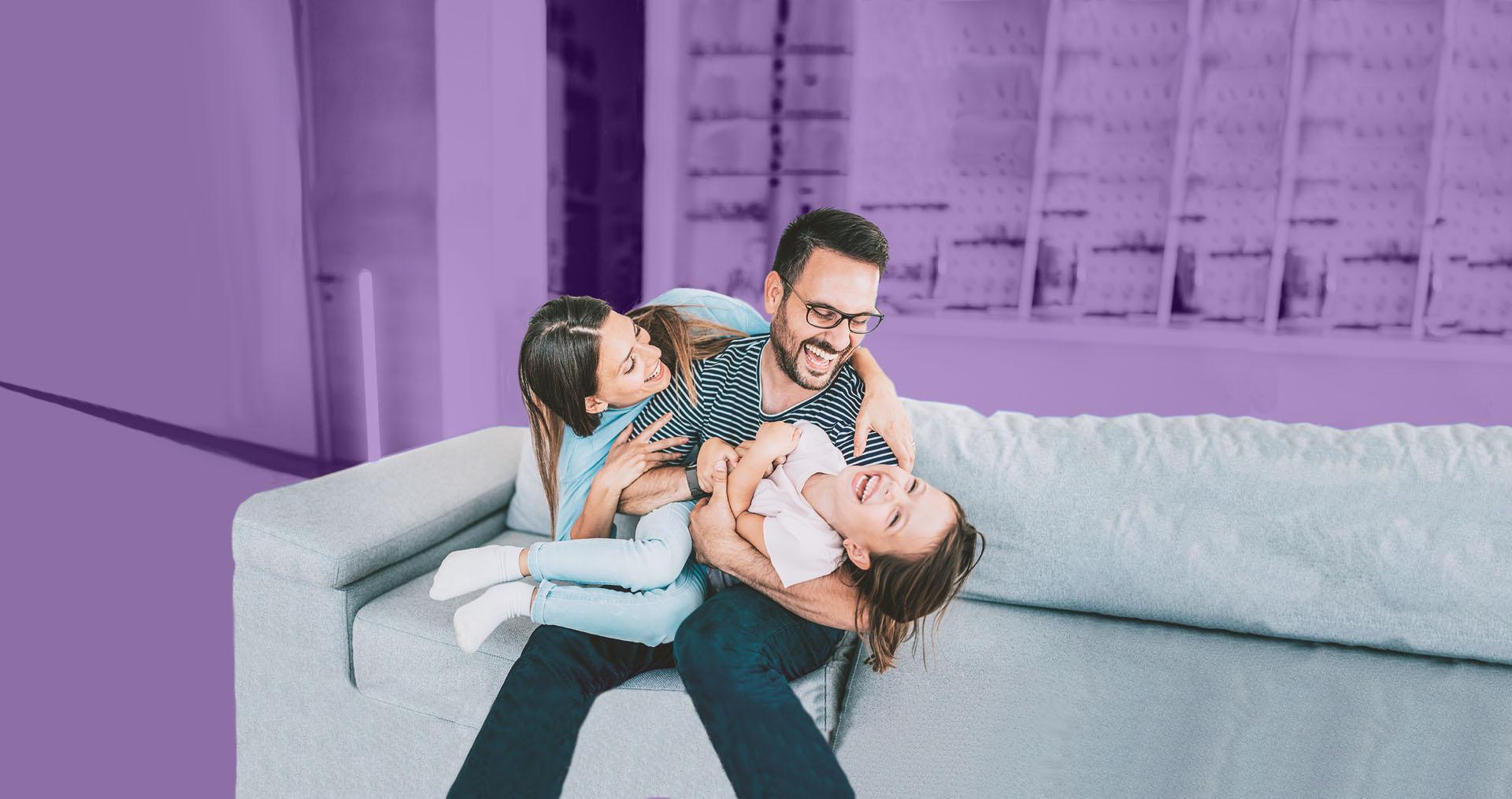 Image of a family laughing 和 sitting on a couch
